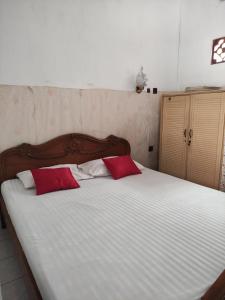 1 cama grande con 2 almohadas rojas. en Fortuna Guest House en Yogyakarta