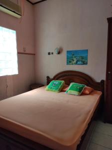 una camera da letto con un letto con due cuscini verdi di Fortuna Guest House a Yogyakarta