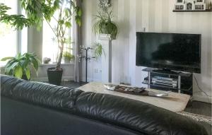 ein schwarzes Ledersofa im Wohnzimmer mit einem Flachbild-TV in der Unterkunft Stunning Home In lvdalen With Sauna in Älvdalen
