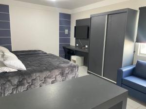 a hotel room with a bed and a blue chair at Hotel Veneza in Cuiabá