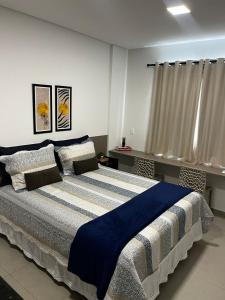 ein Schlafzimmer mit einem großen Bett mit einer blauen Decke in der Unterkunft Studio no West Fit Mossoró Alto Padrão in Mossoró
