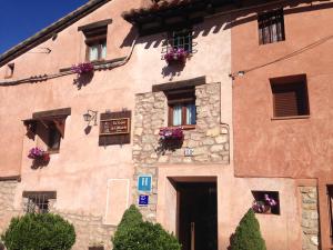 a large stone building with flowers in the windows at Hotel la Casa del Abuelo in Albarracín
