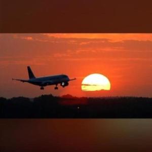 an airplane is flying in front of a sunset at La escala aeropuerto in Luque