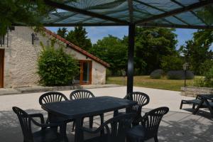 a black table and chairs under an umbrella at Gîte Gers La Métairie in Cézan