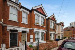 a row of brick houses with a car parked in front at London 2-Bedrooms Apartment in London