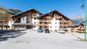 un grand bâtiment avec des voitures garées dans un parking dans l'établissement La Turra 611 - Appt lumineux 8 pers, à Modane