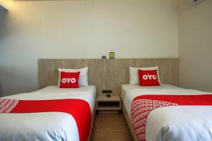 2 bedden in een kamer met rode en witte kussens bij Super OYO 426 All Day Hostel at Sukhmvit in Bangkok