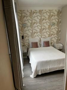 1 dormitorio con cama blanca y pared en Hôtel Marie Louise, en Enghien-les-Bains