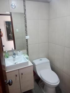 ein Badezimmer mit einem weißen WC und einem Waschbecken in der Unterkunft Departamento 3 habitaciones in Quito