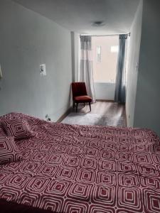 ein Schlafzimmer mit einem Bett und einem roten Stuhl in der Unterkunft Departamento 3 habitaciones in Quito