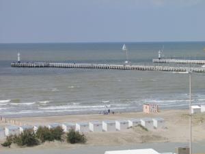 a beach with a pier and the ocean at Hotel Uilenspiegel in Nieuwpoort