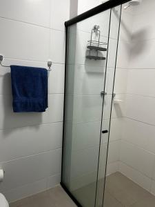 La salle de bains est pourvue d'une douche en verre et d'une serviette bleue. dans l'établissement Studio no West Fit Mossoró Alto Padrão, à Mossoró