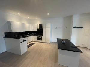 a kitchen with white cabinets and a black counter top at Deluxe Living Krefeld Zentrum, Nähe Düsseldorf in Krefeld