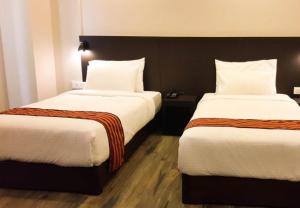 een hotelkamer met 2 bedden met witte lakens bij Hotel Bhutan Ga Me Ga in Phuntsholing