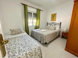 a bedroom with two beds and a window at Apartamento Marinero del Sur in Chiclana de la Frontera