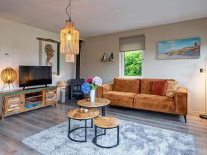 a living room with a couch and a tv at Holiday home near dunes with wellness garden in Den Burg