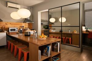 uma cozinha com uma grande mesa de madeira e cadeiras laranja em Chic & Basic Tallers Hostal em Barcelona