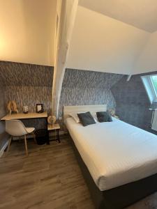 a bedroom with a bed and a table and a desk at Hôtel De Troyes in Troyes