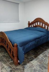 a wooden bed with a blue blanket on it at Lo de Facu in Puerto Pirámides