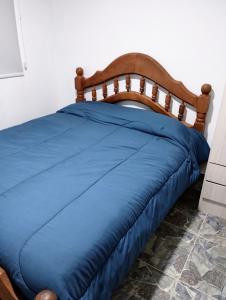 a bed with a blue comforter in a room at Lo de Facu in Puerto Pirámides