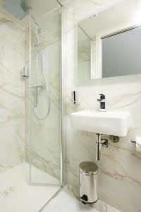 biała łazienka z umywalką i prysznicem w obiekcie VLH Montparnasse Eiffel w Paryżu