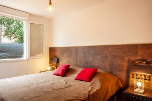 a bedroom with a large bed with two red pillows at Appart - Le Tropical in Ginasservis