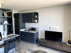 a kitchen with black cabinets and a kitchen with a table at Upmarket Modern 1 Bedroom Apartment in Durban