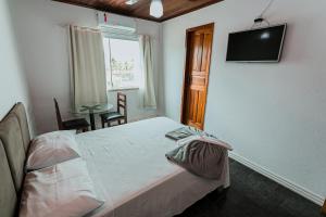 1 dormitorio con 1 cama y TV en la pared en Pousada Paulett's en Ilhéus