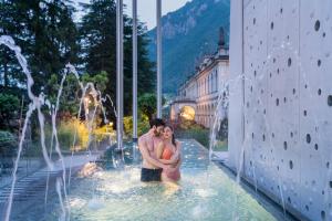 Un uomo e una donna in piedi in una fontana di QC room San Pellegrino a San Pellegrino Terme