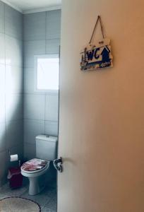 een badkamer met een toilet en een deur met een bord bij Casa-Sobrado próximo à Balsa de Ilha Bela e Rodoviária in São Sebastião