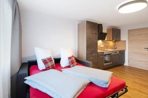 a living room with a red couch and a kitchen at Kaiserchalet in Höchenschwand