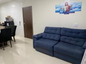 a blue couch in a living room with a table at Apartamento terreo com quintal individual in Patos de Minas