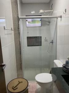 y baño con ducha de cristal y aseo. en Apartamento terreo com quintal individual, en Patos de Minas
