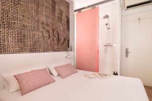 a bedroom with a white bed with two pillows at Chic & Basic Tallers Hostal in Barcelona