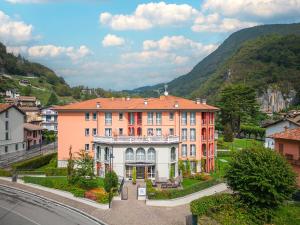 a large building in a town with mountains in the background at QC room San Pellegrino in San Pellegrino Terme