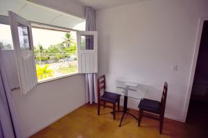 a dining room with a table and chairs and a window at Pousada Paulett's - Hospedagem na Zona Norte de Ilhéus - Bahia in Ilhéus
