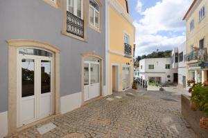 a building with white doors on a cobblestone street at Villa Xique 11 in Monchique