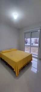 Un dormitorio con una cama con una manta amarilla. en Apartamento dos ingleses, en Florianópolis