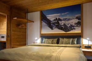 a bedroom with a large bed with a painting on the wall at Chalet Heidi in Kartitsch
