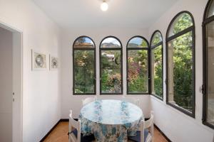 une salle à manger avec une table et quatre fenêtres dans l'établissement Beach Paradise - Cicerone, à Levanto