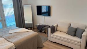 1 dormitorio con cama, sofá y TV en StyleStudio Areena1, en Tampere