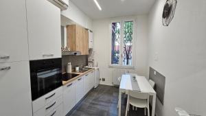 a kitchen with white cabinets and a table and a window at A&D apartments in Bologna
