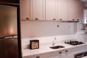 uma cozinha com armários brancos e uma pia em Apartamento pura vida no Parque Una com vaga de garagem. em Pelotas