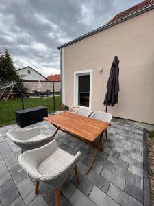 a patio with a wooden table and chairs and an umbrella at Moderne 2 Zimmer-Ferienwohnung in Nörten-Hardenberg