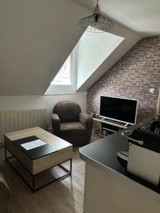 uma sala de estar com uma poltrona e uma televisão em Le studio du square: beauval em Romorantin-Lanthenay