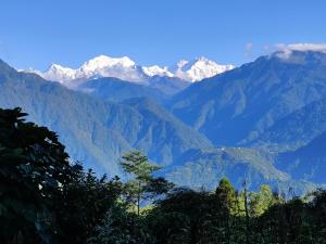 a view of a mountain range with snow capped mountains at Wake In Himalayas in Pelling