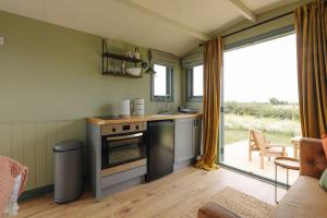 a kitchen with a stove top oven next to a window at Clover Hut - Snettisham Meadows in Snettisham