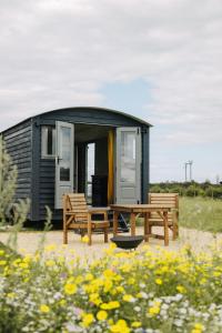 a tiny house with two benches and a table at Clover Hut - Snettisham Meadows in Snettisham