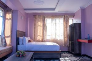 a bedroom with purple walls and a bed with a window at Hotel Good Putt in Nakuru