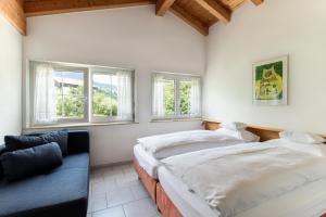 2 camas en una habitación con sofá y ventanas en Tgesa Romana, en Savognin